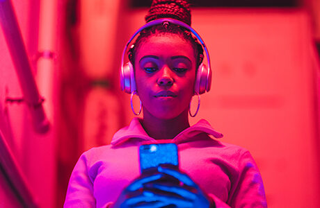 Portrait of young black woman listening to music under neon lights